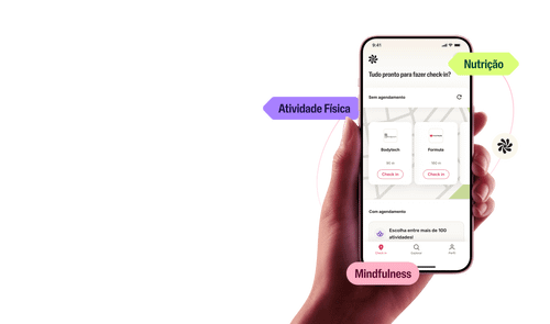 Uma mão segura um celular, que mostra o app do Wellhub onde se pode ver os destaques para check-ins em atividades físicas e bem-estar. 