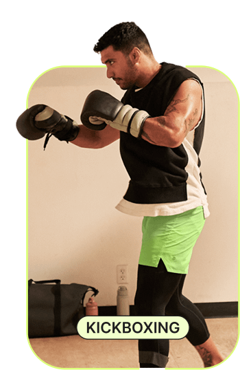 An image shows a man wearing boxing gloves getting ready for his kickboxing class. 