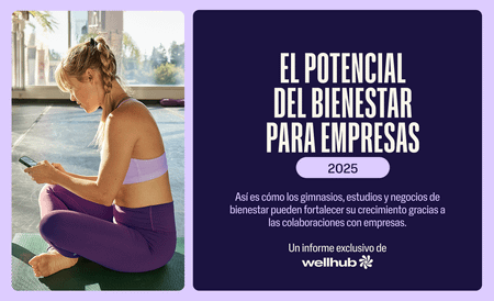 Mujer en ropa deportiva sentada usando el móvil, junto a un cartel de Wellhub sobre el bienestar para empresas 2025.