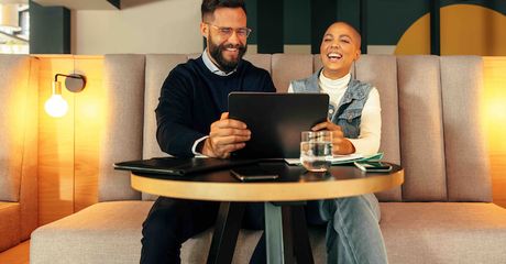 Two coworkers laughing while looking at a computer screen.