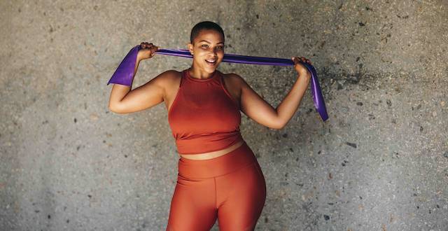 A woman posing for a picture while holding a stretching band.