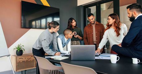 A group of coworkers looking over paperwork in a meeting room.