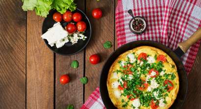 Receita fitness de omelete saudável com ovos, tomate, queijo branco e folhas verdes em frigideira