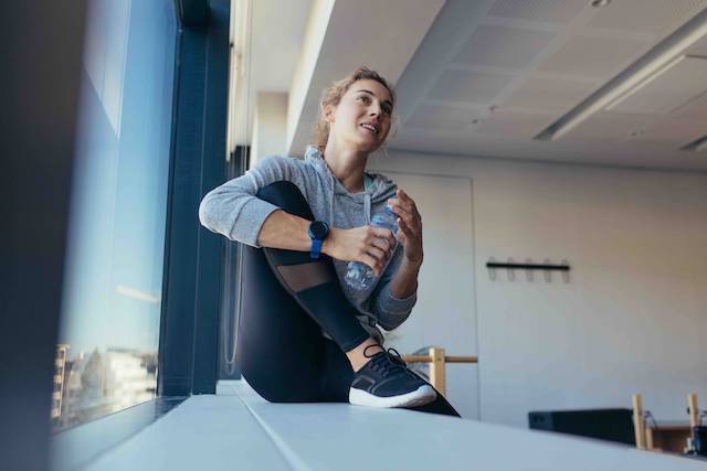 Woman stretching while drinking water.