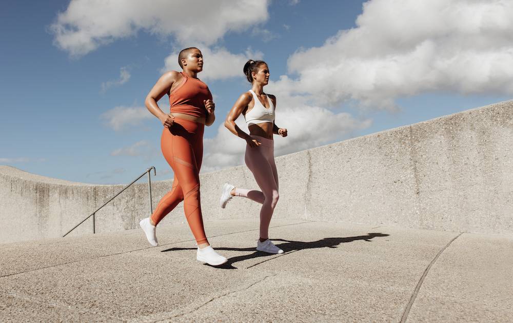 Two women wearing gym clothes, running.