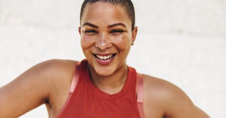 Woman wearing gym clothes smiling at the camera.