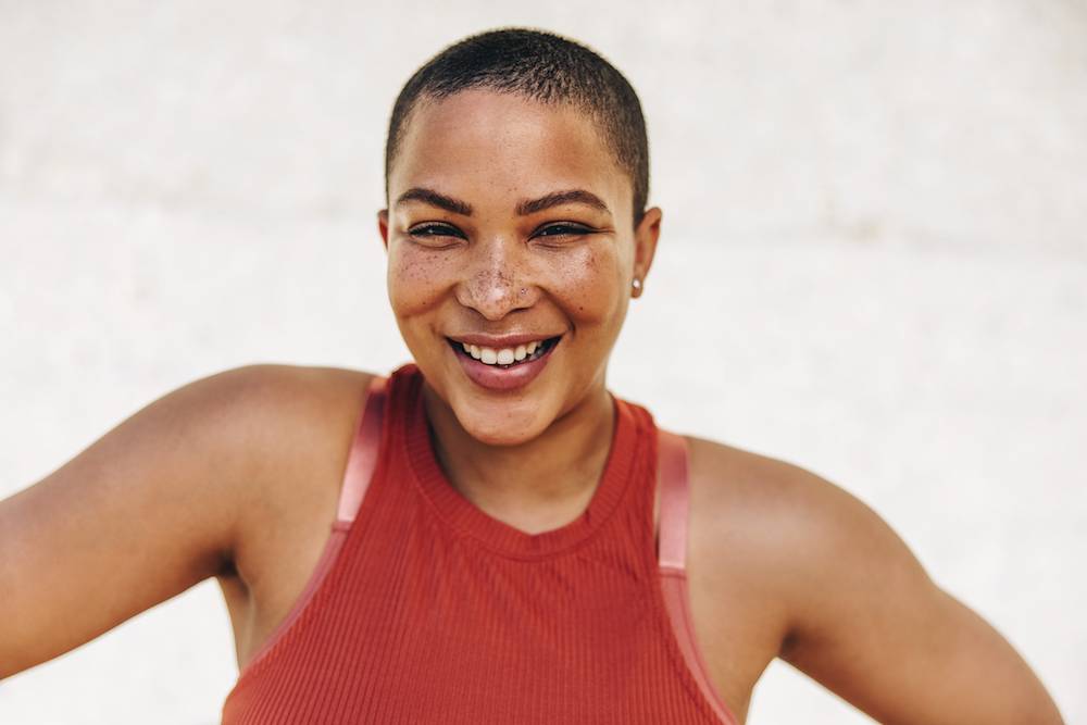 Woman wearing gym clothes smiling at the camera.