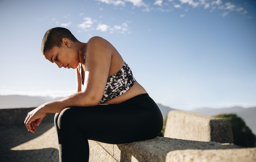 Woman sitting, with her head down, looking tired or sad.