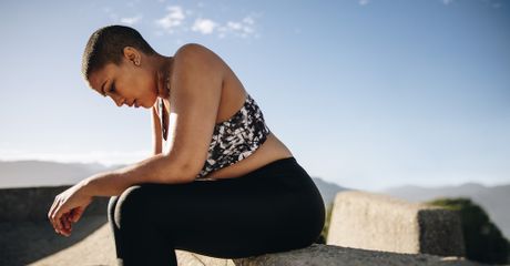 Woman sitting, with her head down, looking tired or sad.