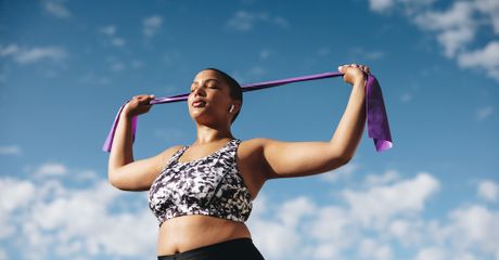 Woman standing up, with her eyes closed, stretching.