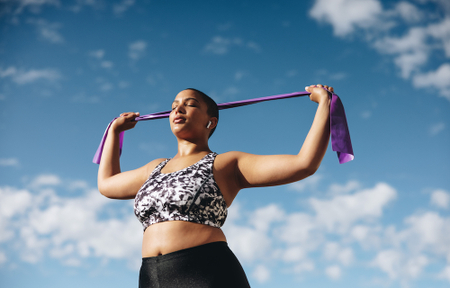 Woman standing up, with her eyes closed, stretching.