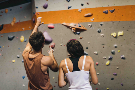 A man and a woman rock climbing in a gym.