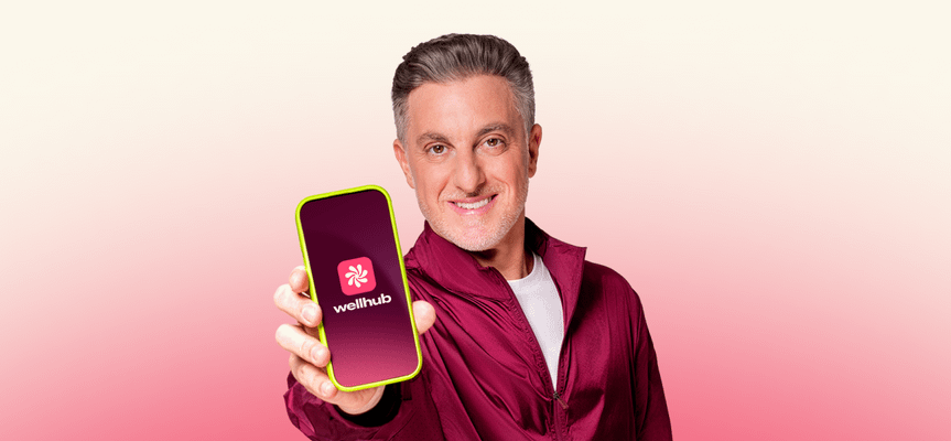 luciano huck segurando celular com o aplicativo do Wellhub